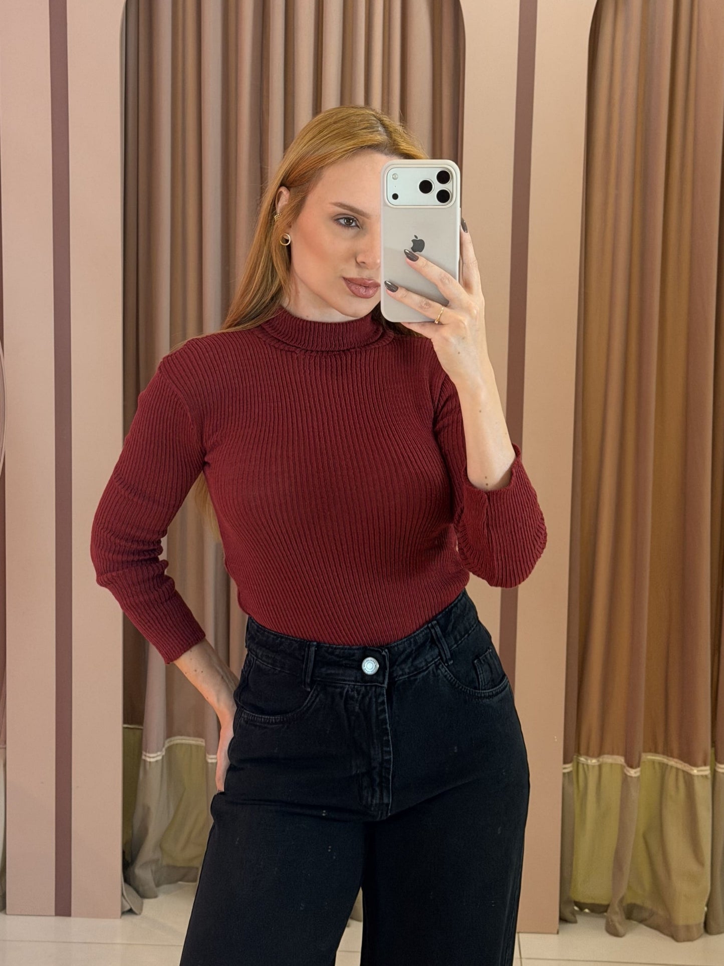 Modelo vestindo blusa cacharrel feminina em tricô canelado vinho com gola alta e manga longa, combinada com calça preta.
