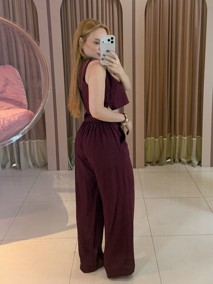 Modelo vestindo conjunto feminino risca de giz marsala composto por cropped sem mangas e calça pantalona de cintura alta.